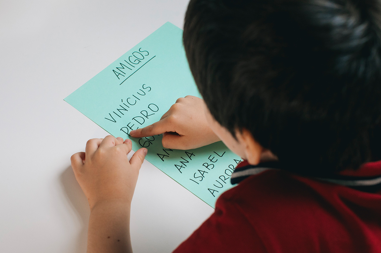 Fotografia de aluno olhando para lista com o nome dos alunos.
