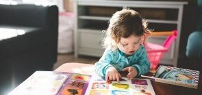 Bebê olha para páginas coloridas de livro infantil