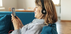Mulher com fones no ouvido e celular na mão
