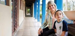 Uma professor ao lado de um aluno, eles olham para a foto