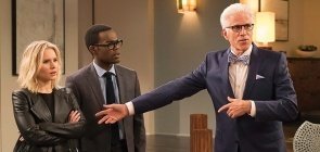 Três pessoas, mais à direita uma mulher loira, ela está surpresa. Ao seu lado, um homem negro, usando oculos e terno completo à dua direita um homem mais velho de cabelo branco e oculos usa terno azul 