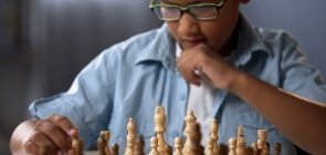 Estudante pensa diante d um tabuleiro de xadrez