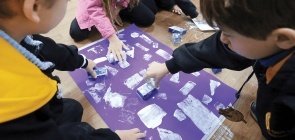 Foto de grupo de crianças pintando cartaz com moldes de figuras